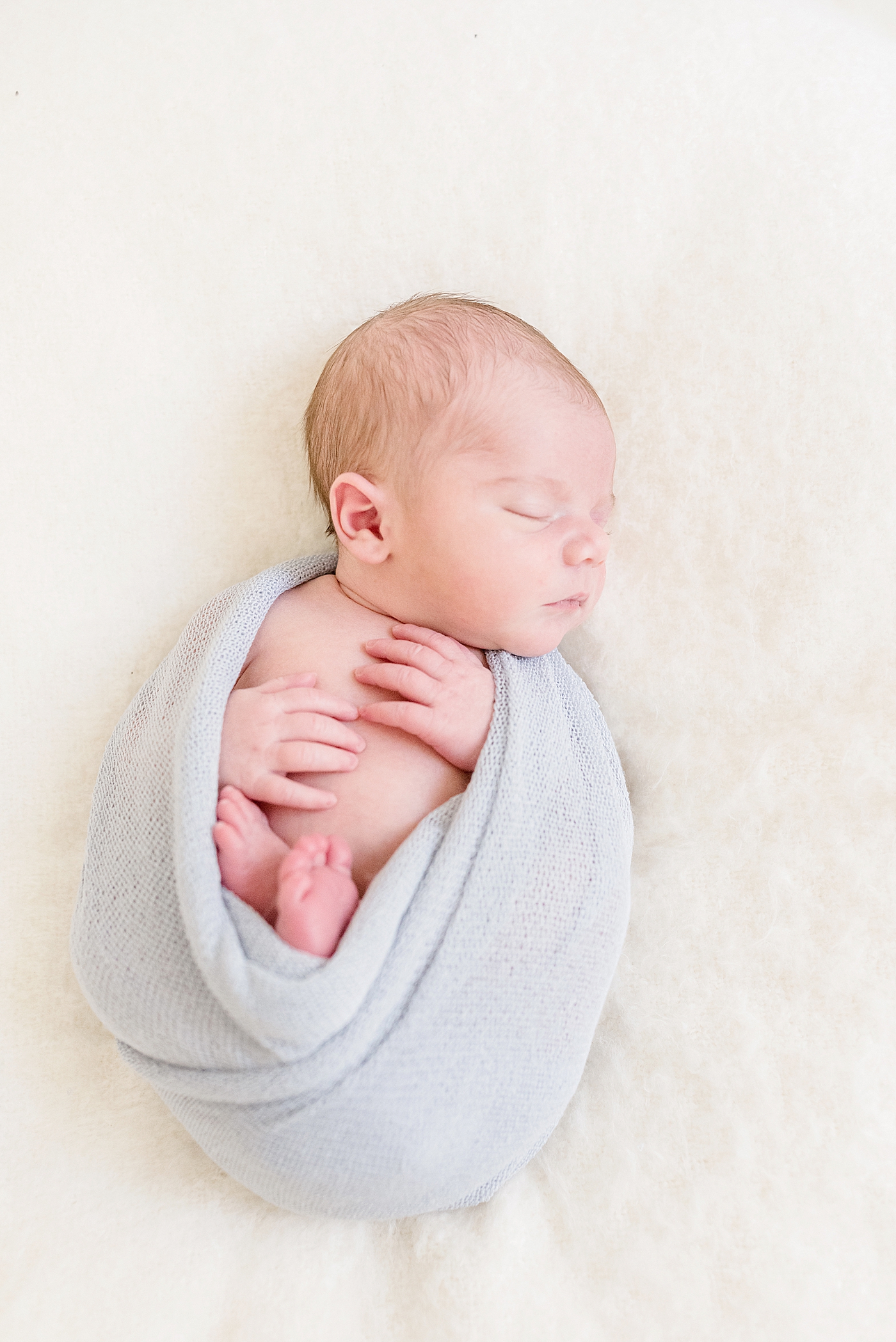 Sleeping newborn in a gray swaddle | Photo by Anna Wisjo Photography