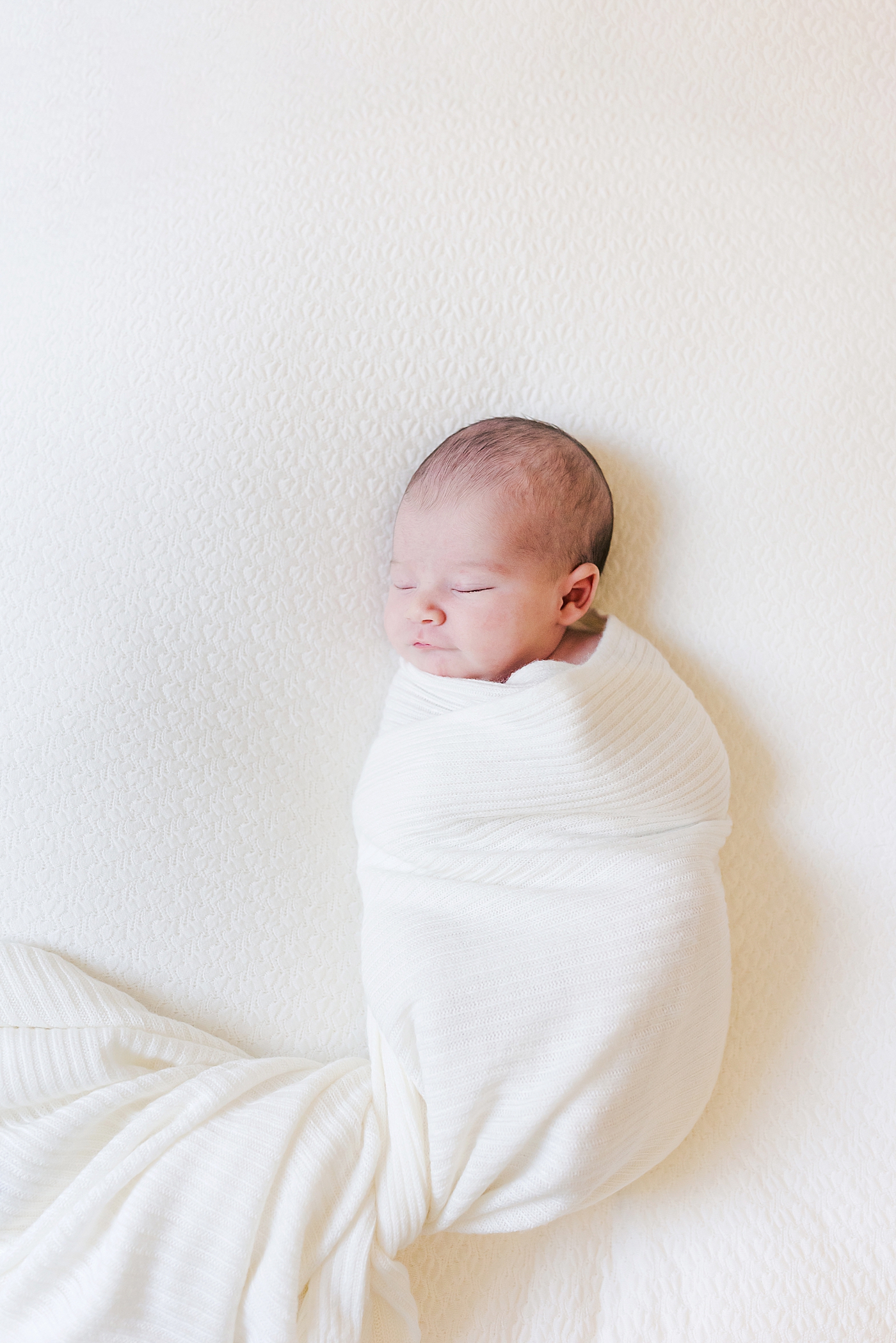 Baby girl in a white swaddle sleeping | Photo by Ballantyne newborn photographer Anna Wisjo 