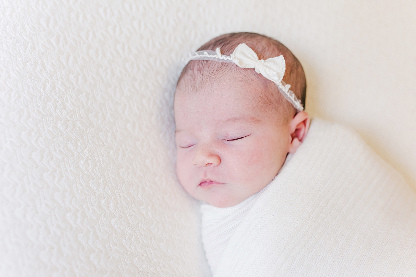 Sleeping baby girl with a headband wrapped in a swaddle | Photo by Ballantyne newborn photographer Anna Wisjo 
