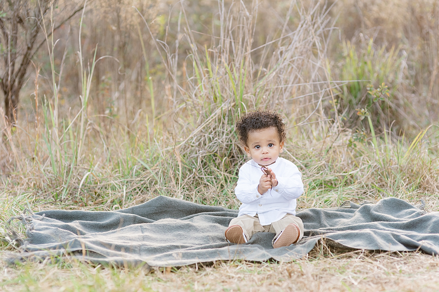 Baby boy sitting on a blanket playing with leaves | Photo by Anna Wisjo Photography