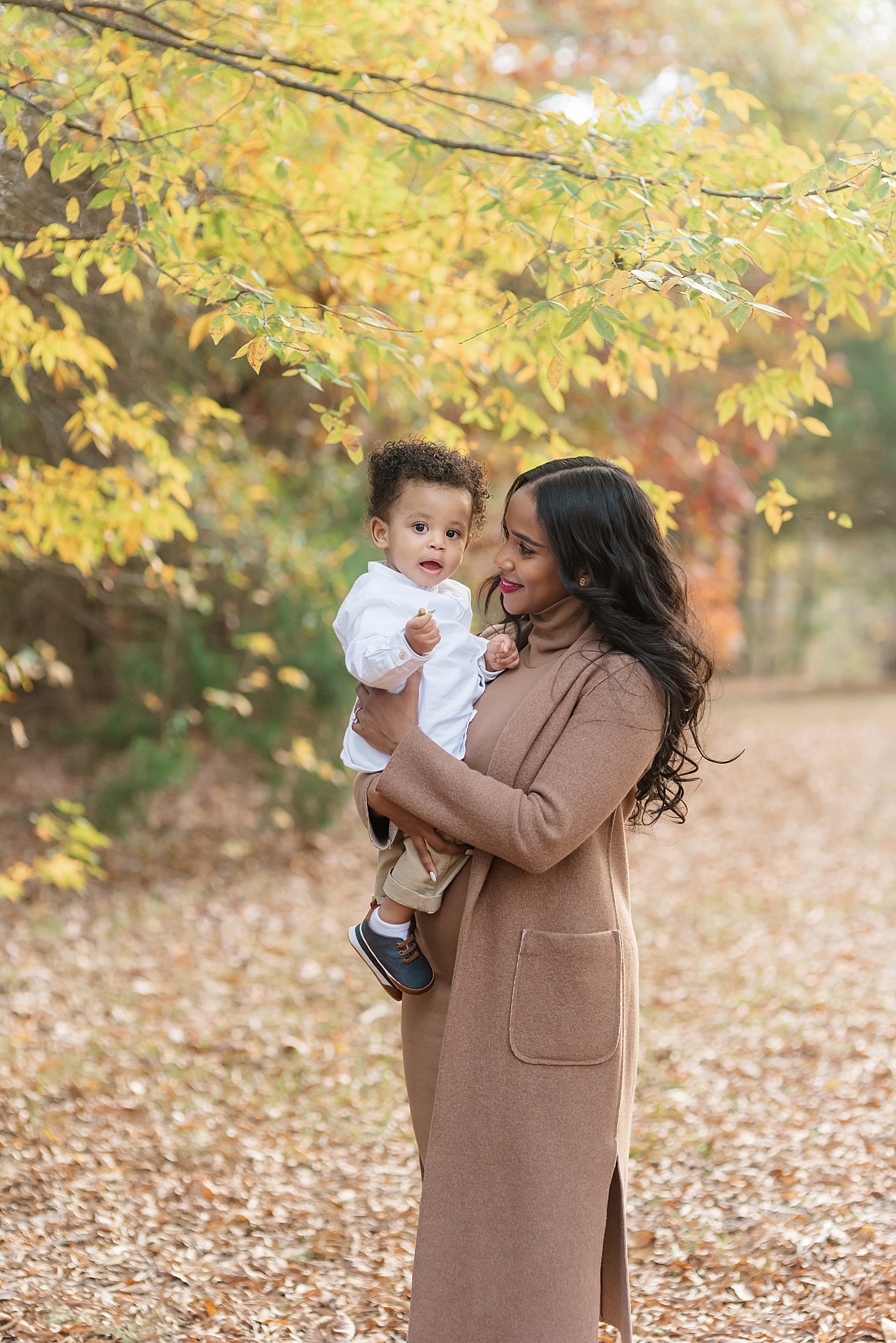 Mom in brown coat holding her baby boy in white | Photo by Anna Wisjo Photography