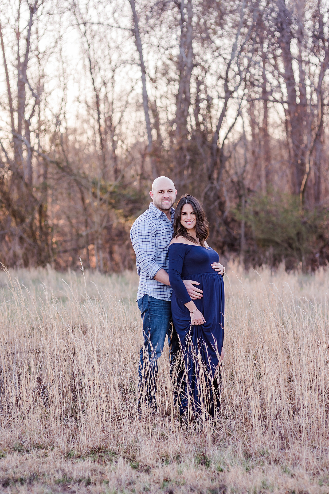 Mom and dad to be in blue in a field | Photo by Anna Wisjo Photography