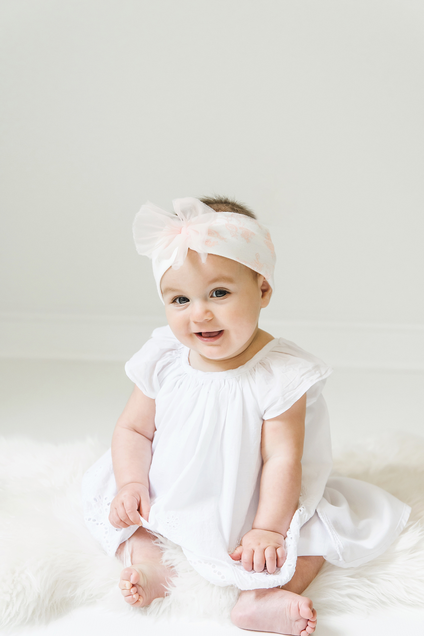 Baby girl with pink and white headband sitting up in the studio | Baby photographer in Charlotte Anna Wisjo