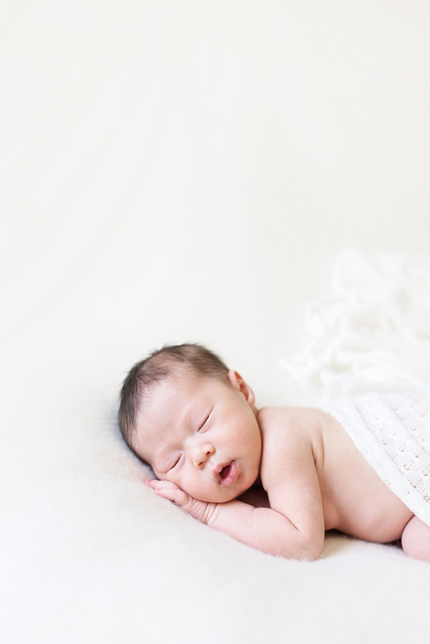 Sleeping newborn baby girl in a white blanket | Photo by Anna Wisjo Photography