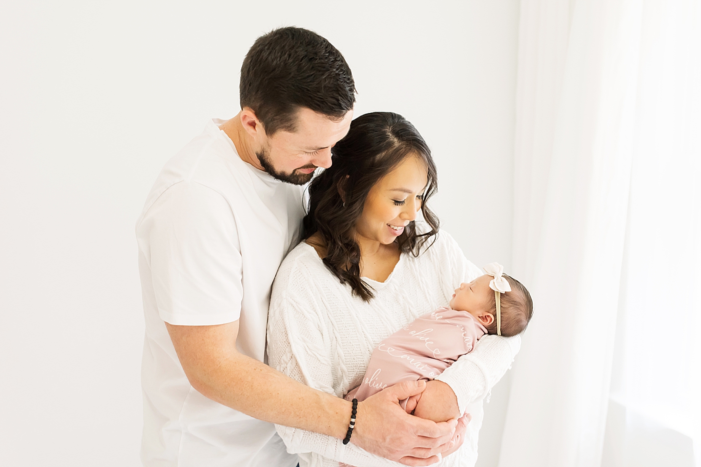 Mom and dad holding their newborn baby girl | Photo by Anna Wisjo Photography
