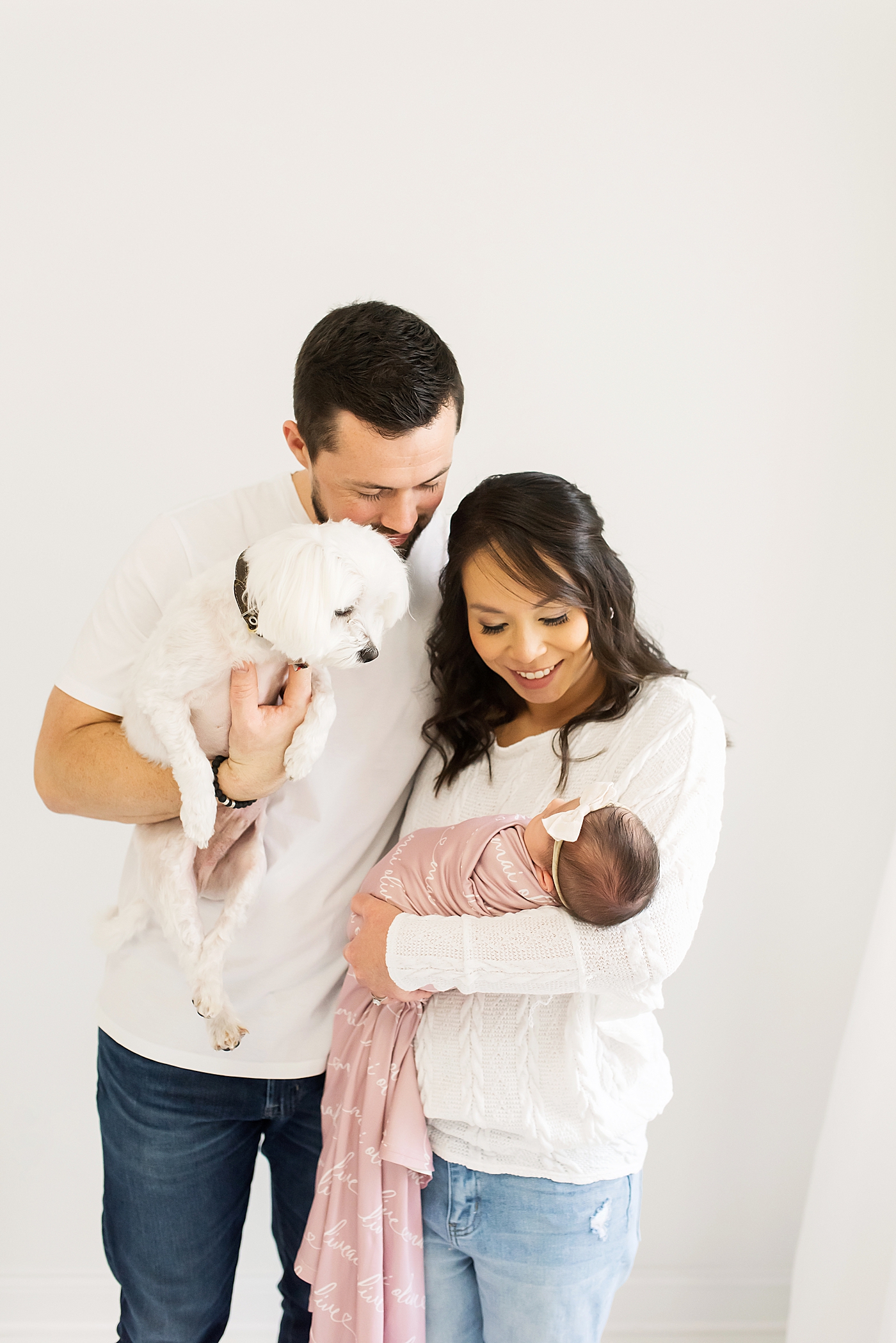 Mom and dad holding their puppy and newborn baby girl | Photo by Anna Wisjo Photography