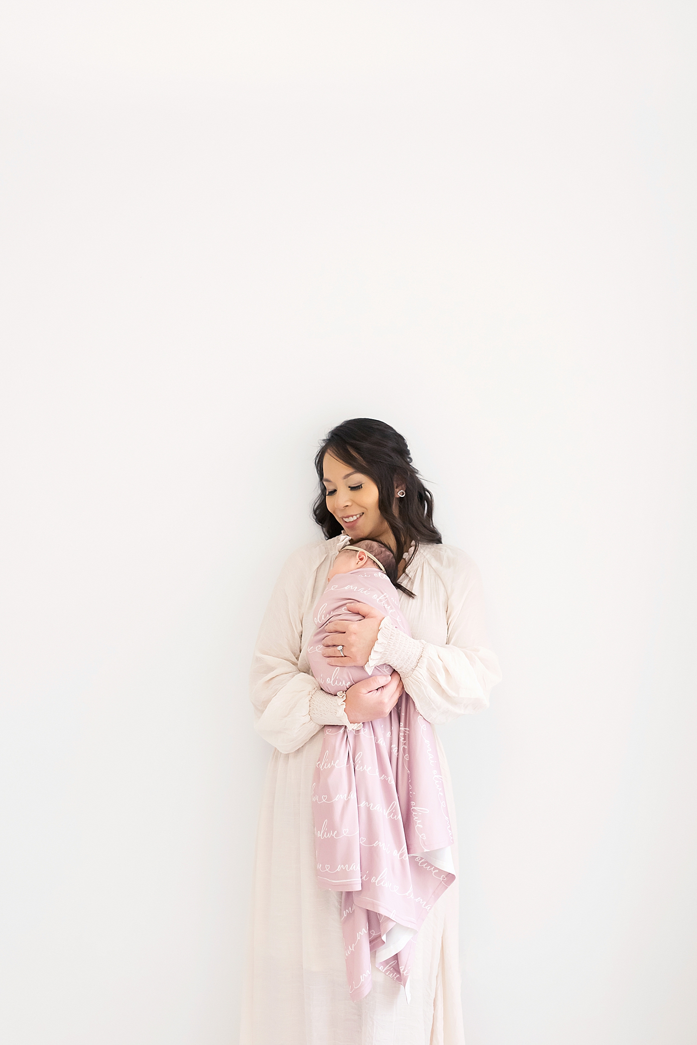 Newborn studio session for baby girl wrapped in pink held by mom | Photo by Anna Wisjo Photography