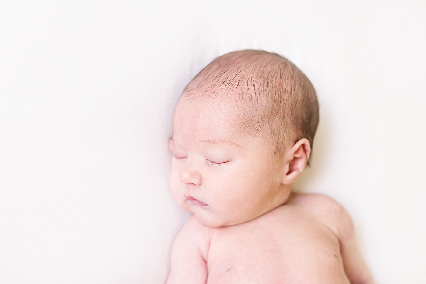 Sleeping newborn baby girl on a white surface | Photo by Anna Wisjo Photography 