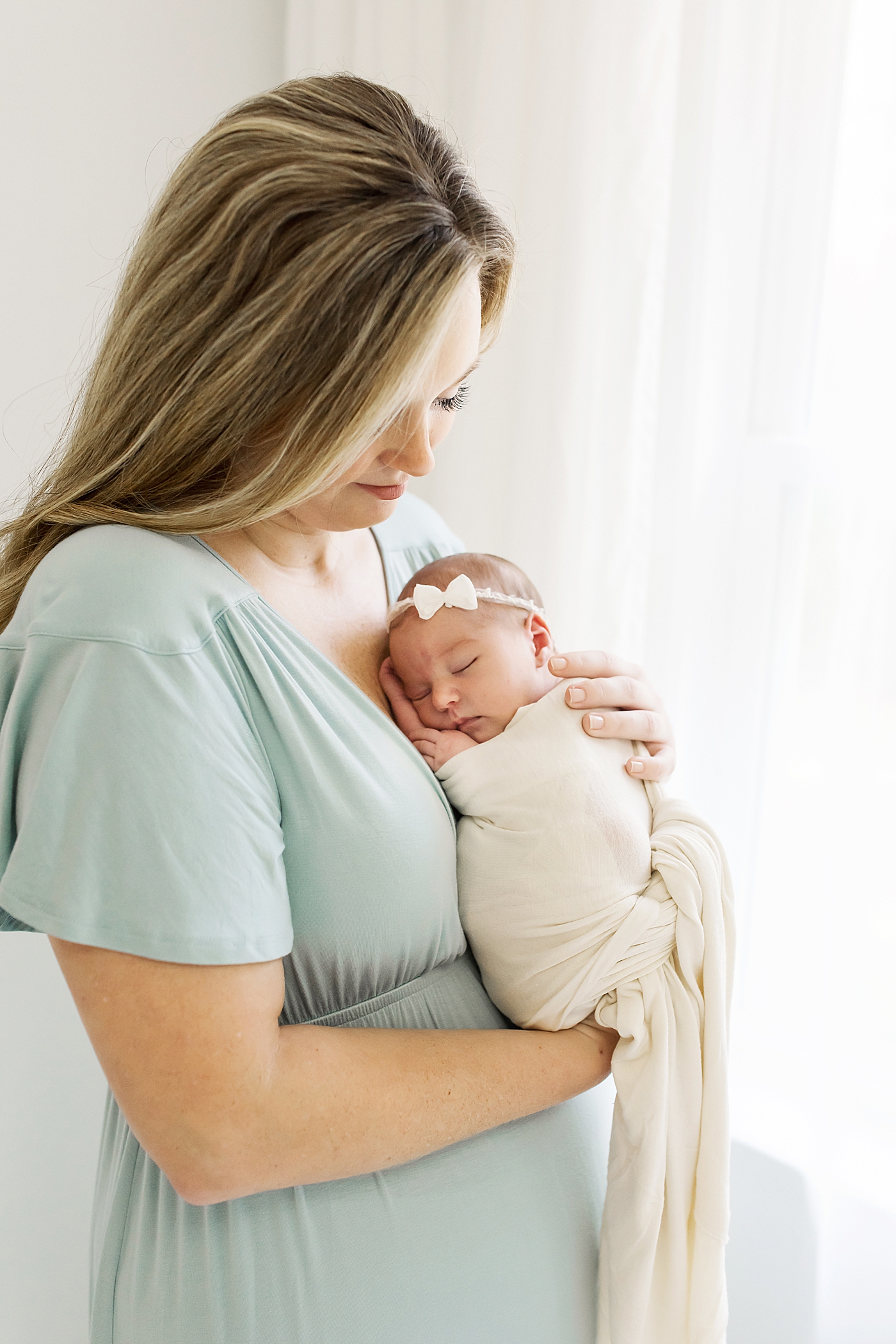 Mom in a light blue dress holding her sleeping baby girl | Photo by Anna Wisjo Photography 