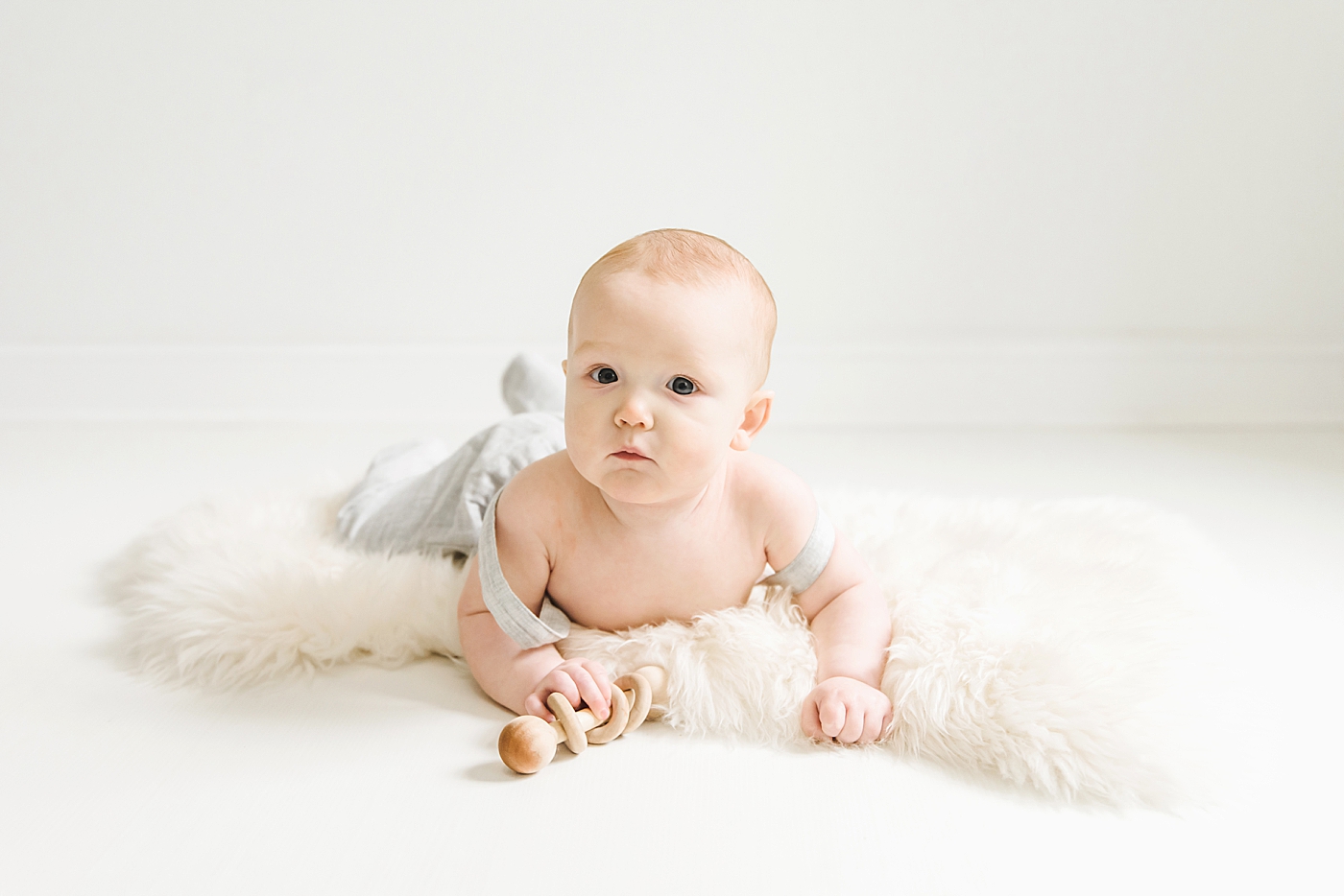 Baby boy in overalls laying on his stomach | Photo by Anna Wisjo Photography 