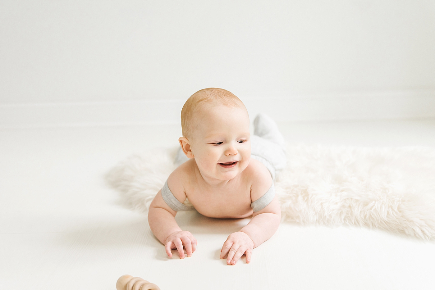 Baby boy smiling laying on a fuzzy rug | Photo by Anna Wisjo Photography 
