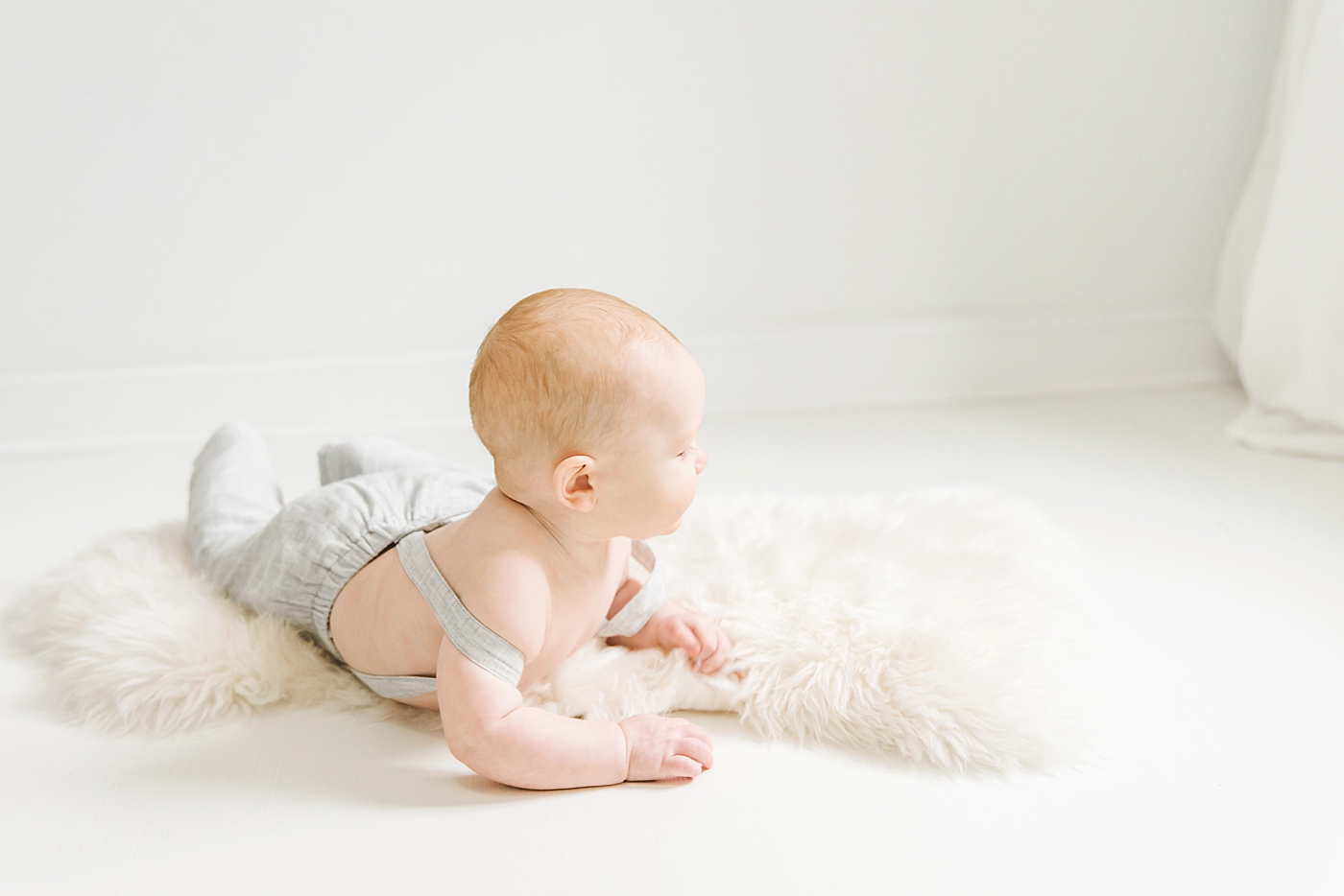 Babt boy in overalls laying on a fuzzy rug | Photo by Anna Wisjo Photography 