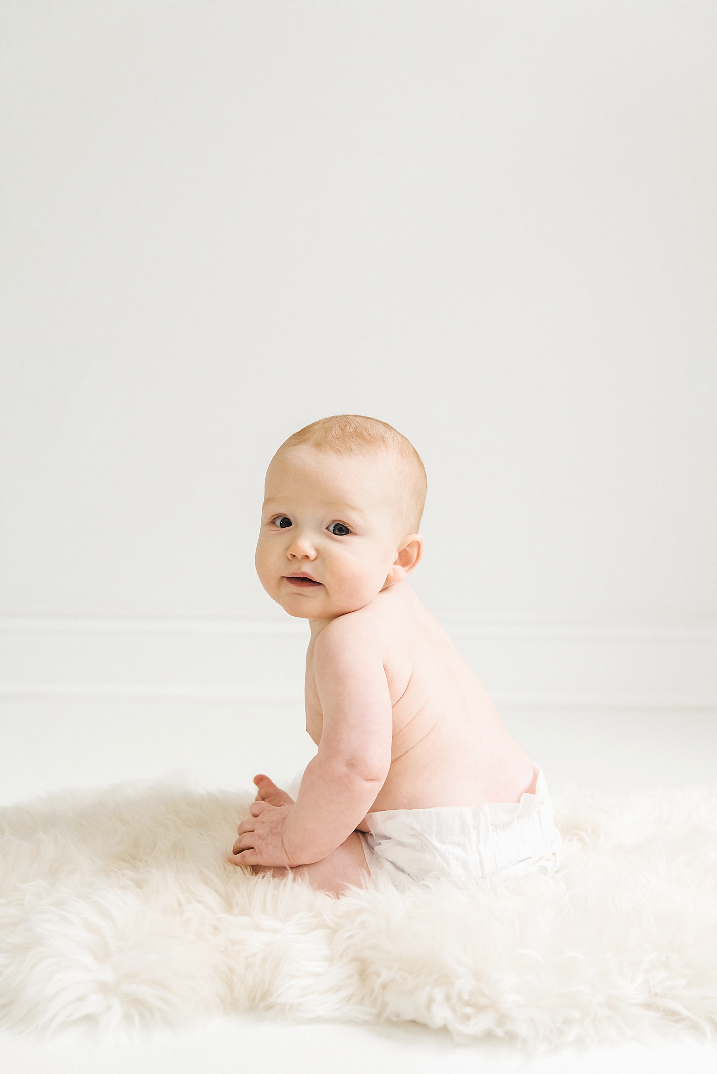 Baby boy sitting on a fuzzy rug | Photo by Denver NC milestone photographer Anna Wisjo