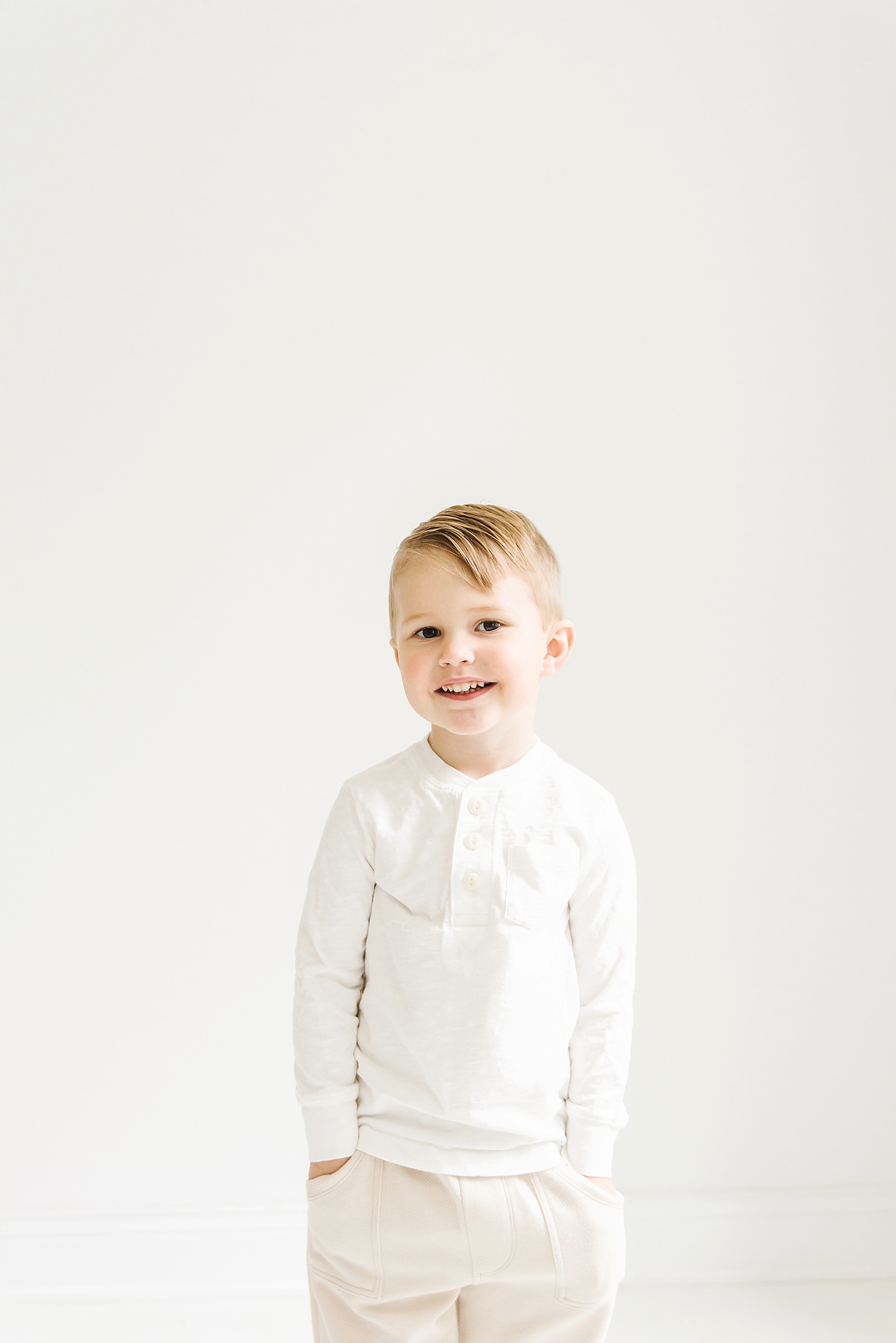 Little boy in white with his hands in his pockets | Photo by Denver NC milestone photographer Anna Wisjo